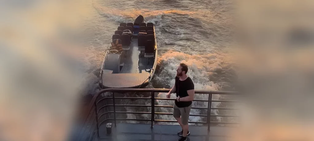 Heiko steht am Heck des Schiffes und auf das Beiboot.