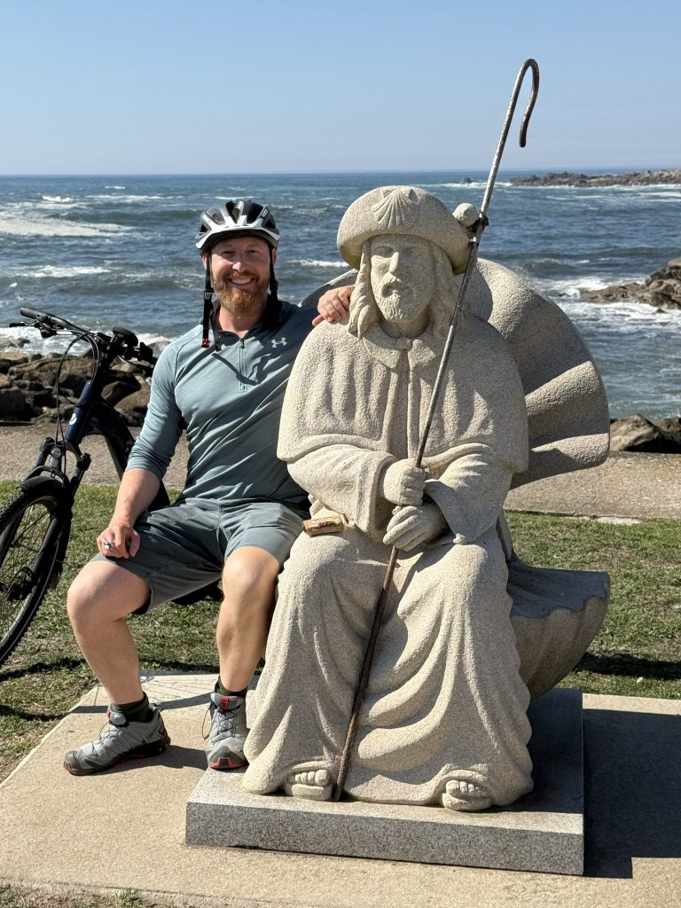 Heiko Lackstetter mit Fahrrad neben einer Jakobusfigur am Atlantik