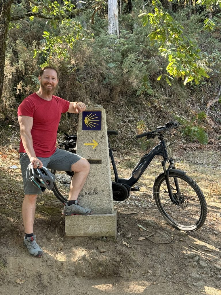 Heiko Lackstetter mit Fahrrad an einem Wegweiser des Jakobswegs in Galicien