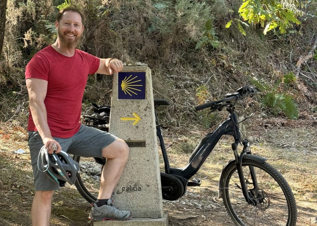 Heiko Lackstetter mit Fahrrad an einem Wegweiser des Jakobswegs in Galicien