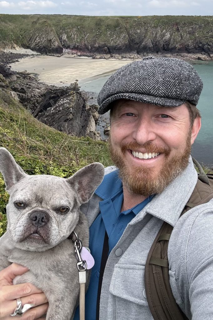 Heiko macht mit Mila ein Selfie vor der felsigen Bucht von Caerfai Bay.