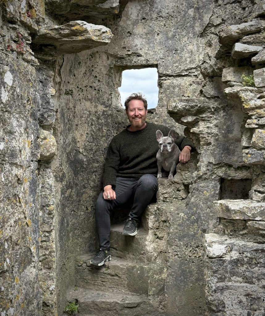 Heiko sitzt mit Mila auf einer Steintreppe in einer Burgruine.