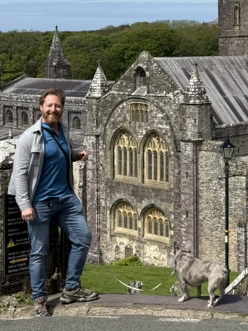 Heiko steht neben dem reich verzierten steinernen Mauerwerk der Kathedrale von St Davids.